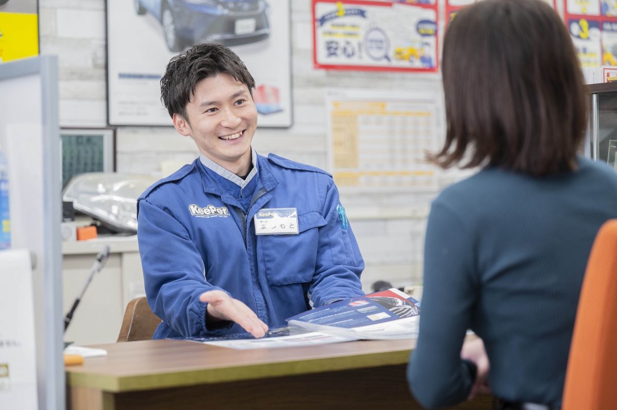 スタッフ（松本さん？）とお客さまが車両を見ながら相談している様子。笑顔で最適プランを提案中